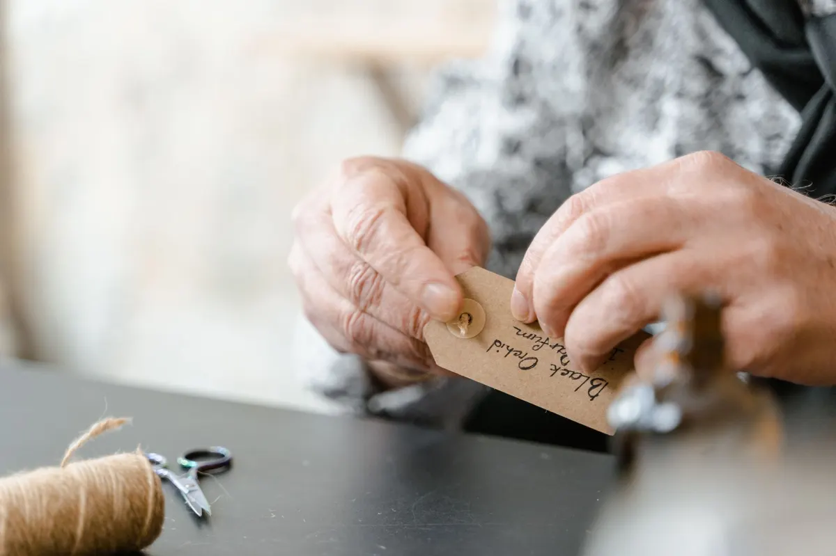 applying vintage french paper label to glass jar close up