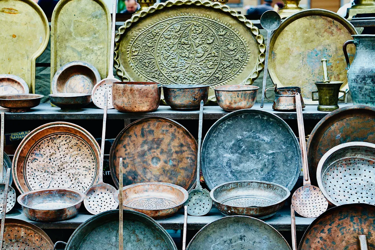 collection of thrifted vintage brass items styled on a bookshelf