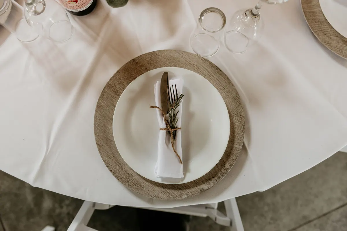 thanksgiving place setting folded linen napkin rosemary sprig plate