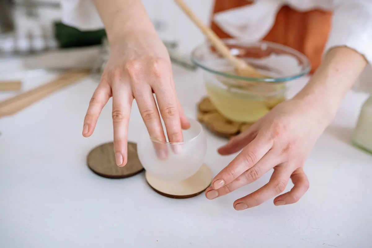 hands applying gold wax to the edge of a hand-painted dark green wooden box close-up